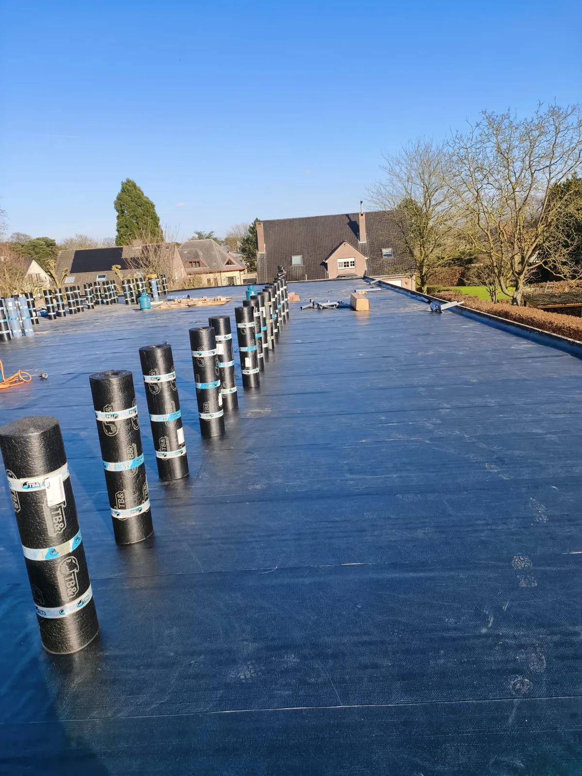 Nieuwe roofing op een groot plat dak onder een blauwe lucht